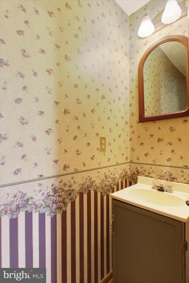 bathroom with wallpapered walls and vanity