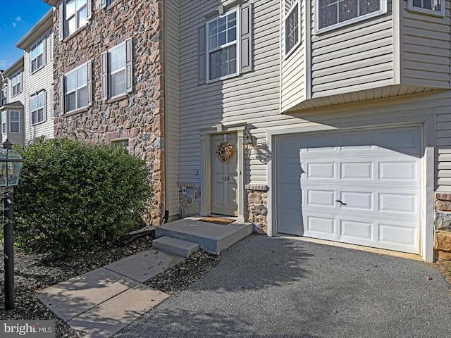 entrance to property with aphalt driveway and stone siding