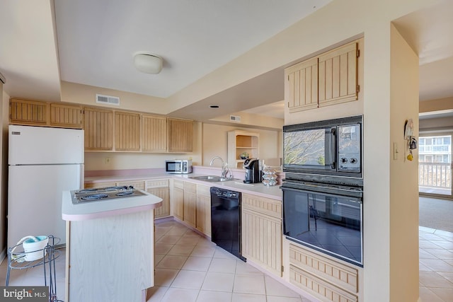 kitchen featuring visible vents, light brown cabinetry, a sink, black appliances, and light countertops