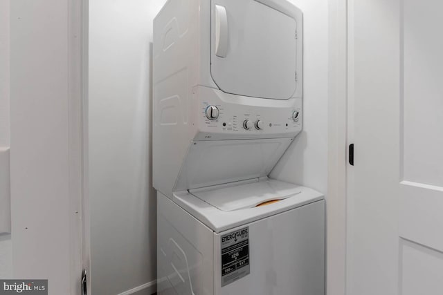 clothes washing area featuring stacked washer and clothes dryer and laundry area