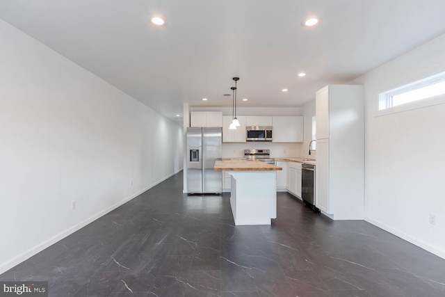 kitchen featuring a kitchen island, baseboards, recessed lighting, appliances with stainless steel finishes, and wood counters