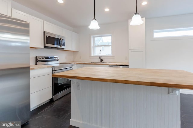 kitchen featuring a sink, white cabinets, wooden counters, and stainless steel appliances