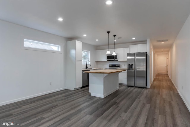 kitchen featuring a center island, dark wood finished floors, wooden counters, and stainless steel appliances