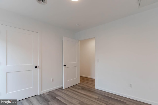 unfurnished bedroom with visible vents, wood finished floors, and baseboards