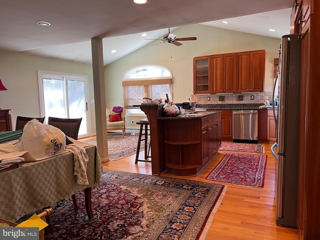 kitchen featuring open shelves, light wood-style floors, appliances with stainless steel finishes, a breakfast bar area, and ceiling fan