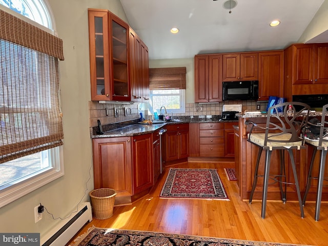 kitchen featuring a baseboard radiator, light wood-style flooring, a sink, decorative backsplash, and black microwave