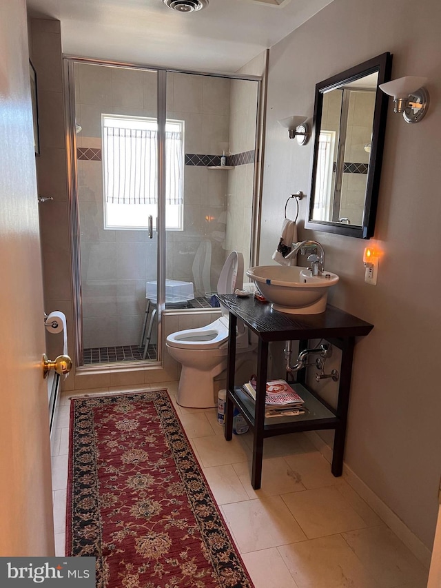 full bath featuring baseboards, a stall shower, a sink, tile patterned floors, and toilet