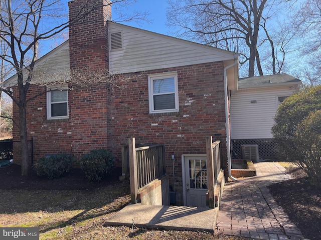 rear view of property featuring brick siding and a chimney