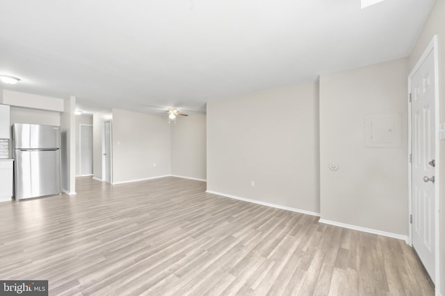 unfurnished living room featuring a ceiling fan, light wood-style floors, and baseboards