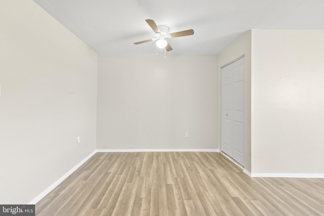 spare room featuring a ceiling fan, baseboards, and light wood finished floors