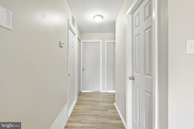 hall with baseboards and light wood-style floors