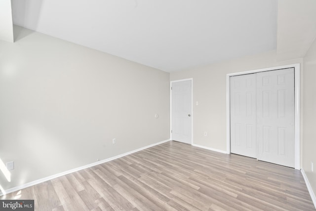 unfurnished bedroom with a closet, light wood-style flooring, and baseboards