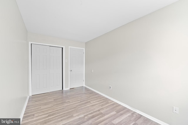 unfurnished bedroom with a closet, baseboards, and light wood finished floors