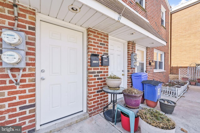 entrance to property featuring covered porch and brick siding