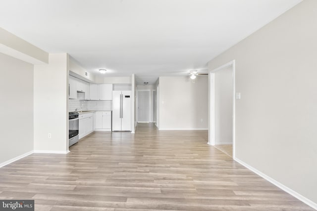 unfurnished living room with visible vents, light wood-style flooring, baseboards, and a sink