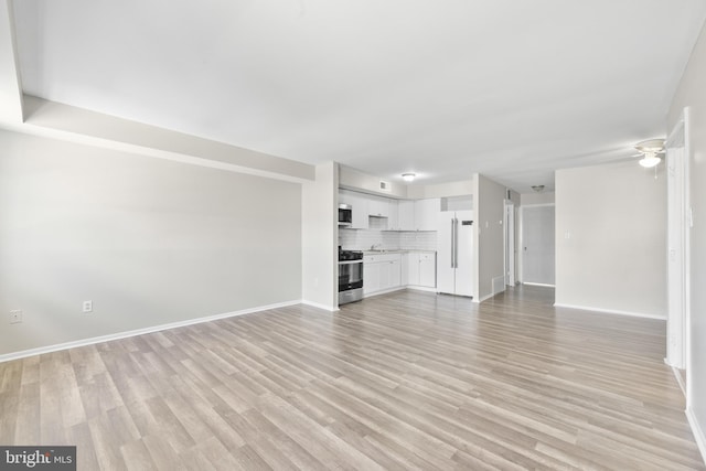 unfurnished living room with light wood-style flooring, baseboards, and ceiling fan