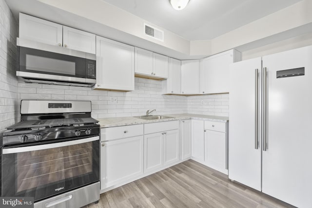 kitchen featuring visible vents, a sink, appliances with stainless steel finishes, white cabinetry, and tasteful backsplash