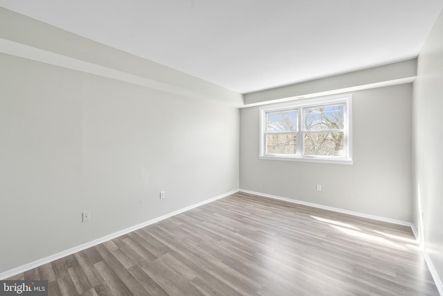 spare room featuring baseboards and wood finished floors