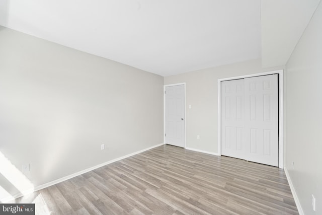 unfurnished bedroom featuring a closet, baseboards, and light wood finished floors