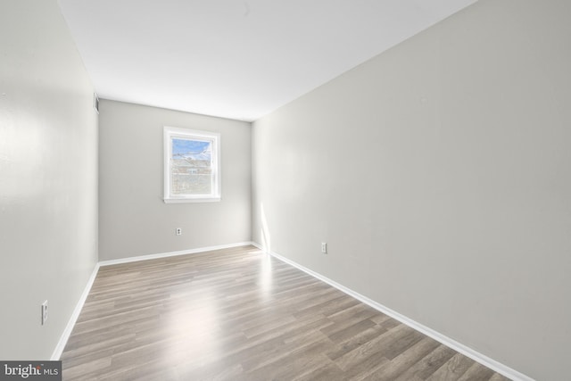 spare room with baseboards and wood finished floors