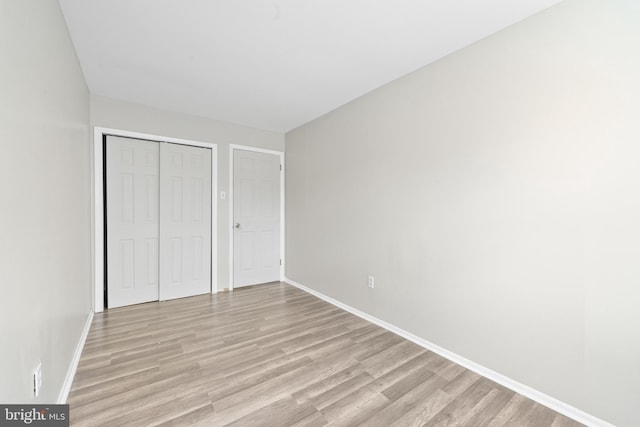 unfurnished bedroom with light wood-style floors, baseboards, and a closet