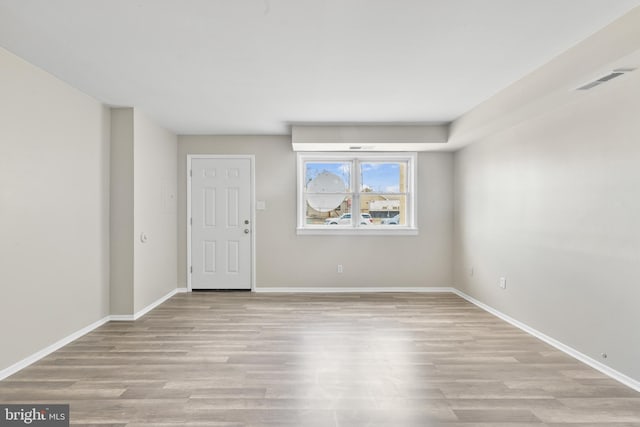 spare room with visible vents, baseboards, and wood finished floors