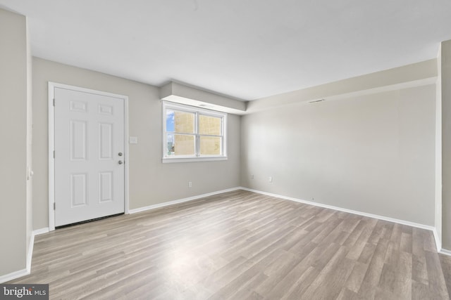 unfurnished room with light wood-type flooring and baseboards