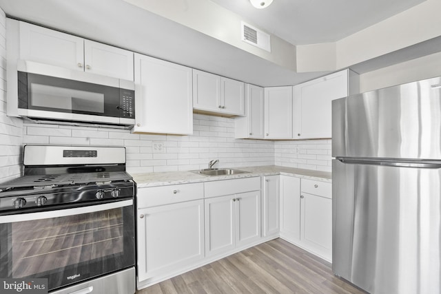 kitchen featuring a sink, decorative backsplash, white cabinets, and stainless steel appliances