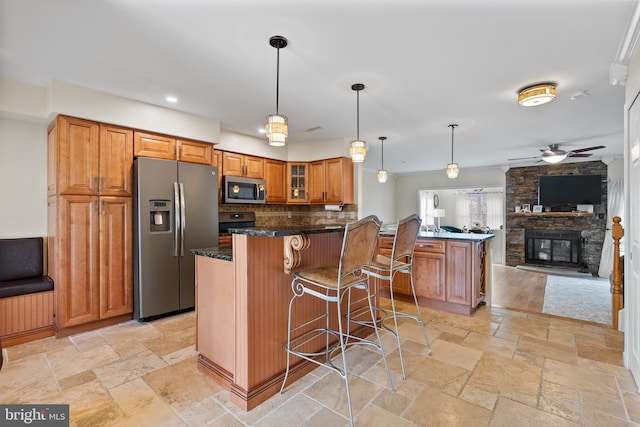 kitchen with a breakfast bar, stone tile floors, appliances with stainless steel finishes, a peninsula, and brown cabinetry