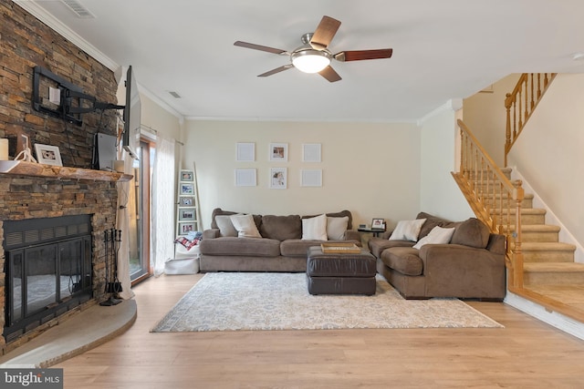 living area featuring ceiling fan, stairs, ornamental molding, a fireplace, and wood finished floors