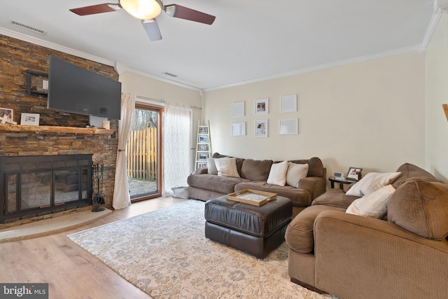 living area featuring visible vents, wood finished floors, ornamental molding, and a ceiling fan