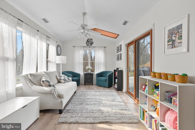 living area featuring visible vents, light wood finished floors, ceiling fan, and vaulted ceiling