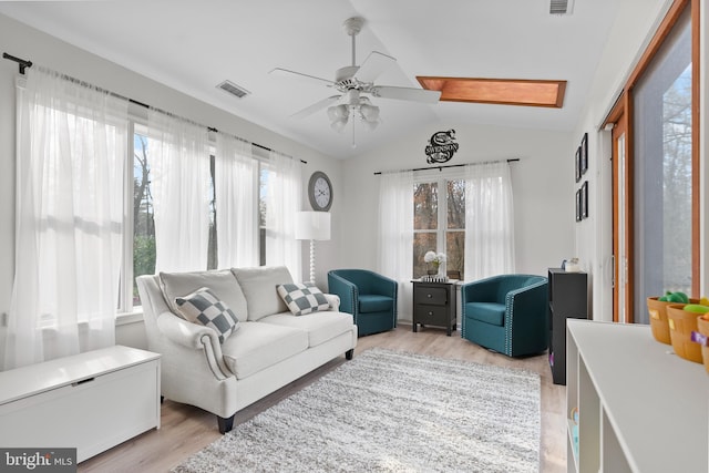 living area with light wood-type flooring, visible vents, ceiling fan, and vaulted ceiling