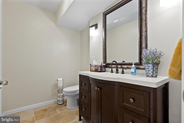 half bathroom featuring baseboards, toilet, and vanity