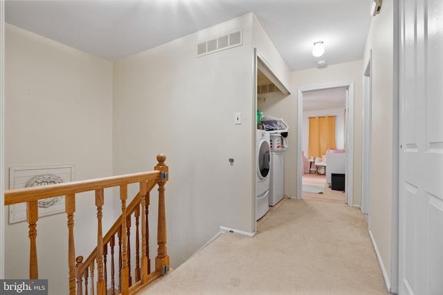 clothes washing area featuring visible vents, baseboards, washing machine and dryer, light carpet, and laundry area