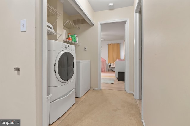 laundry area with visible vents, light colored carpet, washing machine and dryer, and laundry area