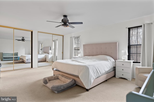 bedroom with multiple closets, light carpet, and ceiling fan