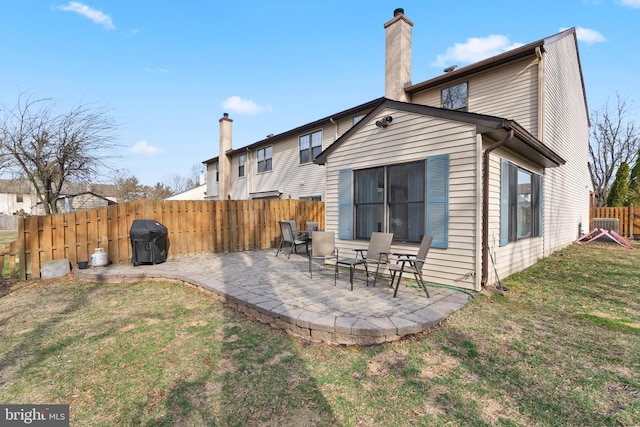 rear view of house featuring a patio, a lawn, a chimney, and fence