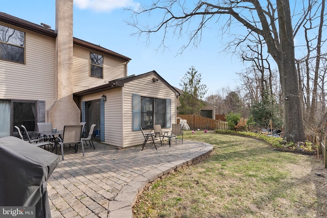 rear view of property featuring outdoor dining space, a patio area, a yard, and fence