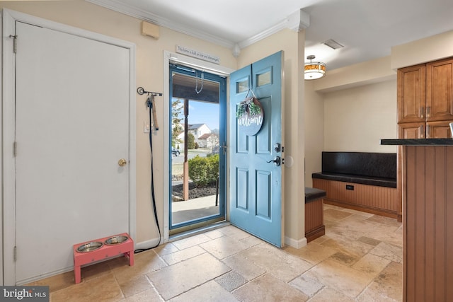 entryway with visible vents, baseboards, stone tile floors, and ornamental molding