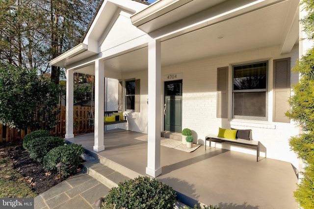 view of patio featuring covered porch and fence