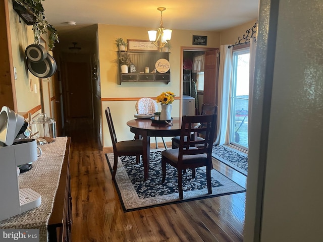 dining space with dark wood-type flooring and a chandelier