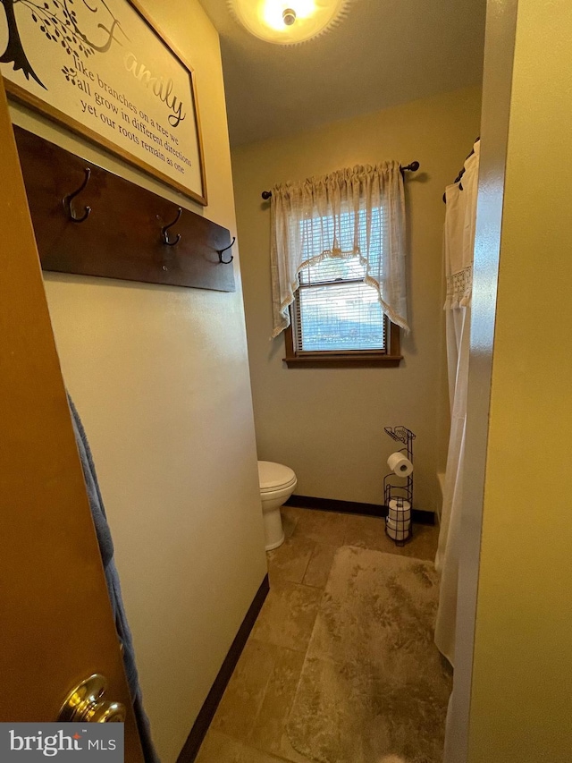 full bath featuring a shower with curtain, baseboards, and toilet