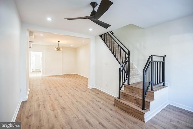 staircase with ceiling fan with notable chandelier, baseboards, and wood finished floors