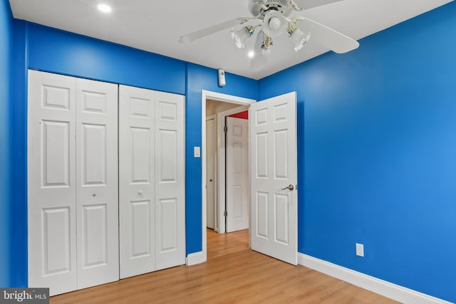 unfurnished bedroom featuring a closet, a ceiling fan, baseboards, and wood finished floors