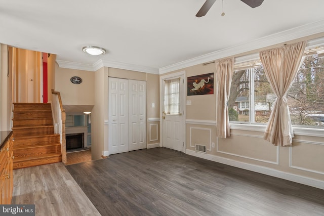 interior space featuring dark wood-style floors, a healthy amount of sunlight, crown molding, and ceiling fan