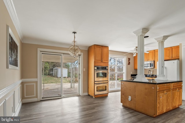 kitchen featuring a sink, dark wood-type flooring, crown molding, appliances with stainless steel finishes, and dark countertops