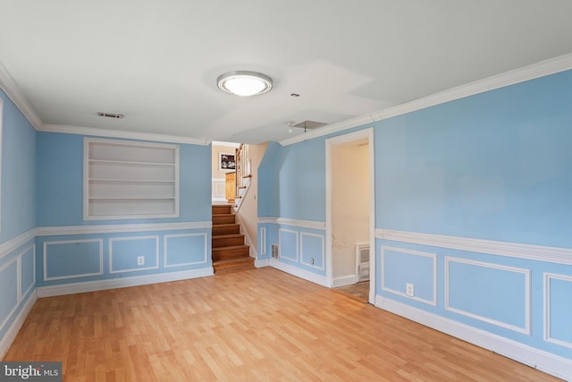 spare room featuring visible vents, built in features, stairs, ornamental molding, and wood finished floors