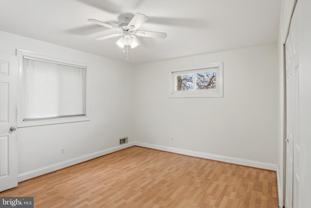 empty room with a ceiling fan, light wood-style flooring, baseboards, and visible vents