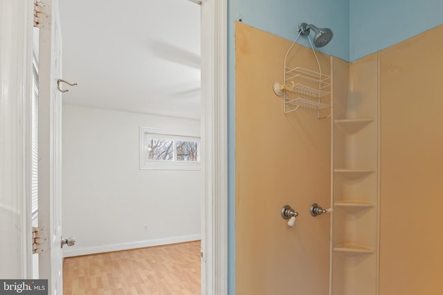 bathroom featuring a shower, baseboards, and wood finished floors